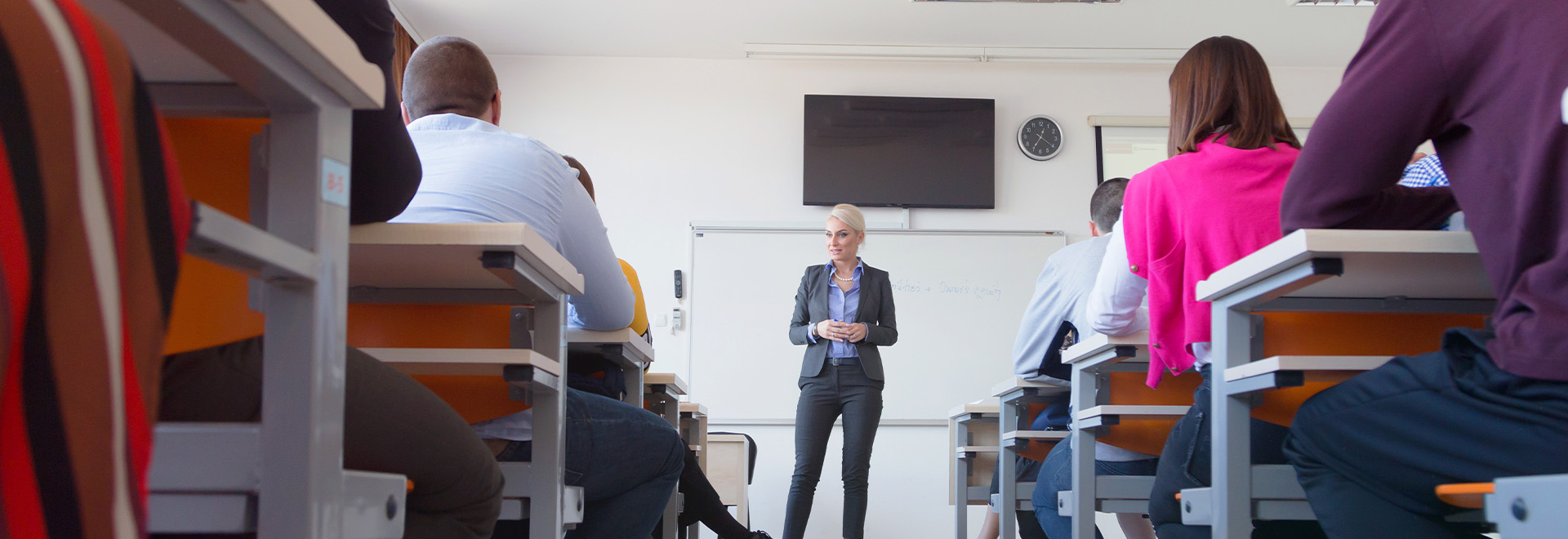 Female attractive professor explain lesson to students and interact with them in the classroom