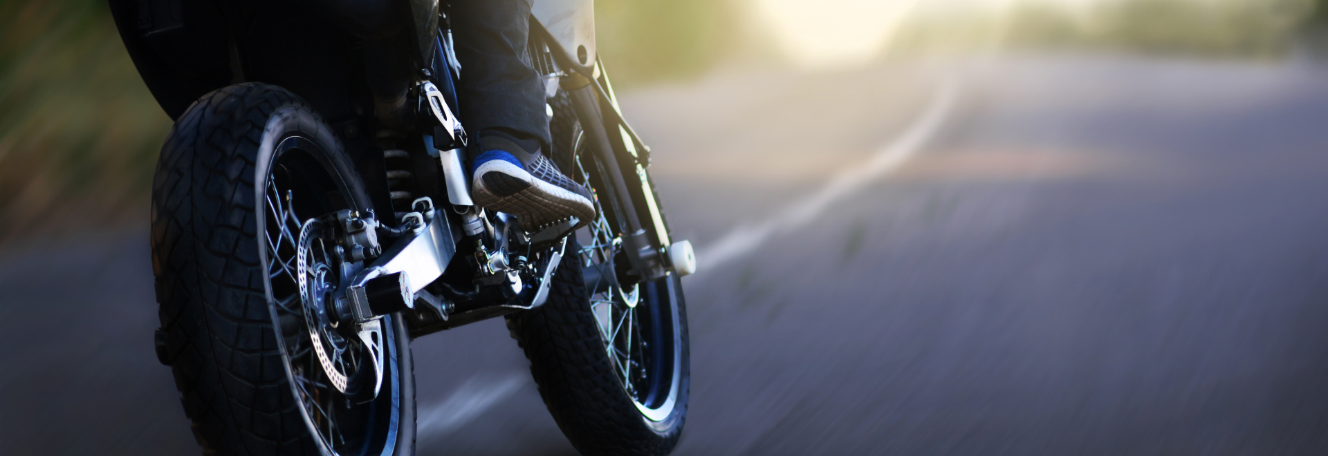 A motorcyclist rides at speed on the highway at sunrise