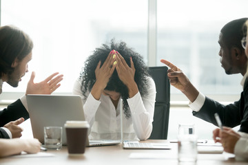 woman with her head down at work while people point at her