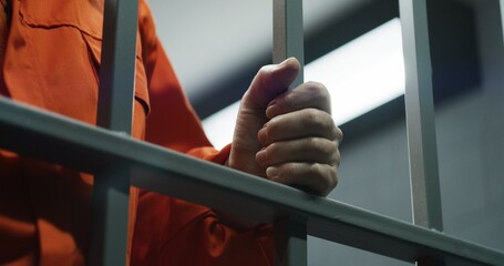 person in jail with hand on cell bar
