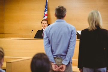 judge, man in handcuffs, and lawyer during criminal trial