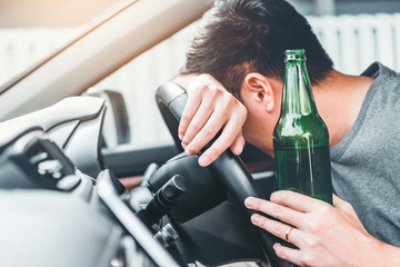 man with beer bottle in car